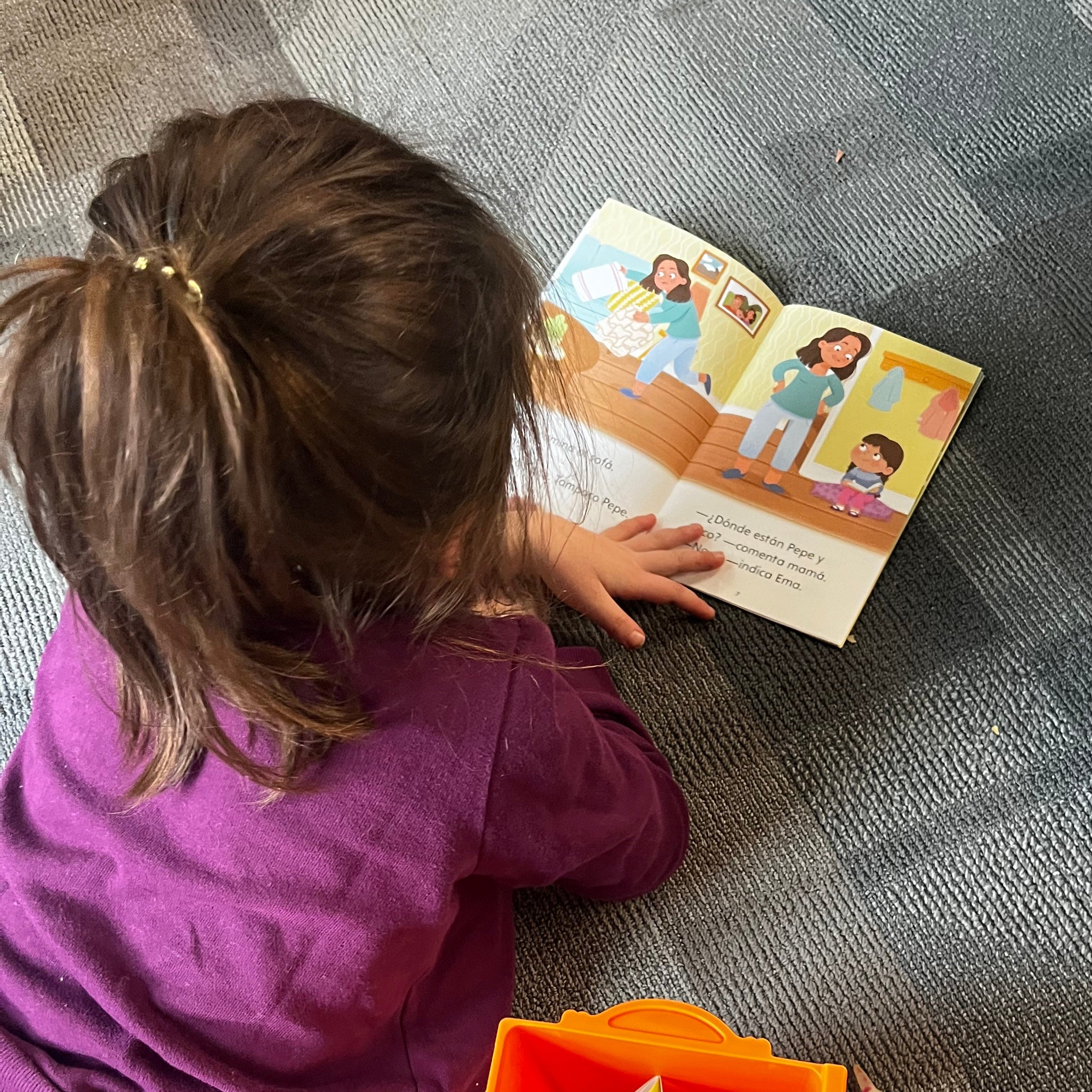 Small child engaged in reading a Spanish decodable book from Hola Books' Kindergarten series