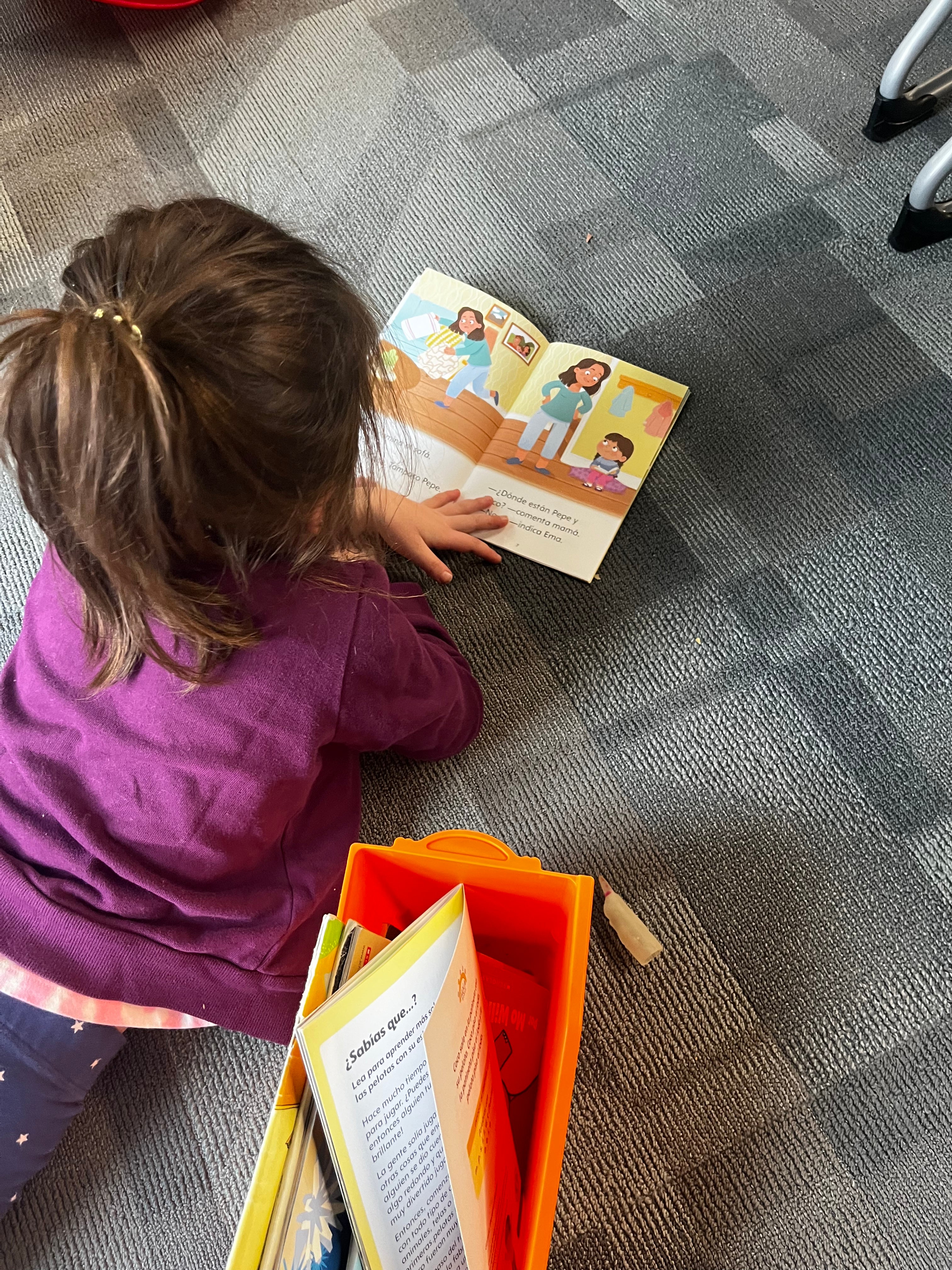 Small child engaged in reading a Spanish decodable book from Hola Books' Kindergarten series